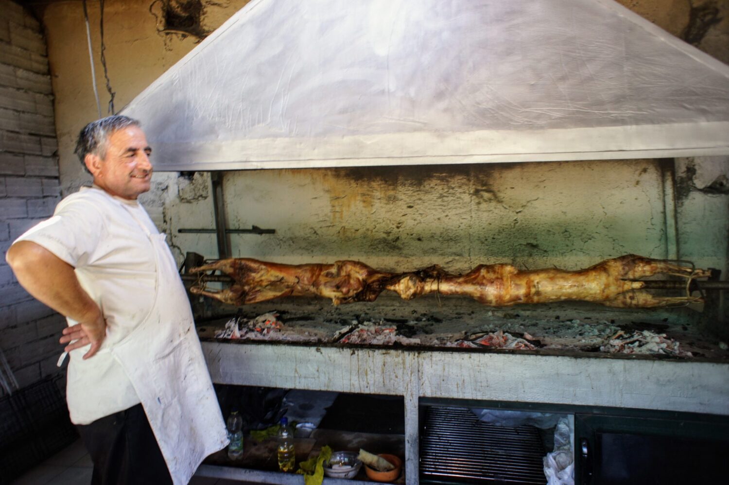 albanian man spit-roasting lamb whole, day trips from tirana